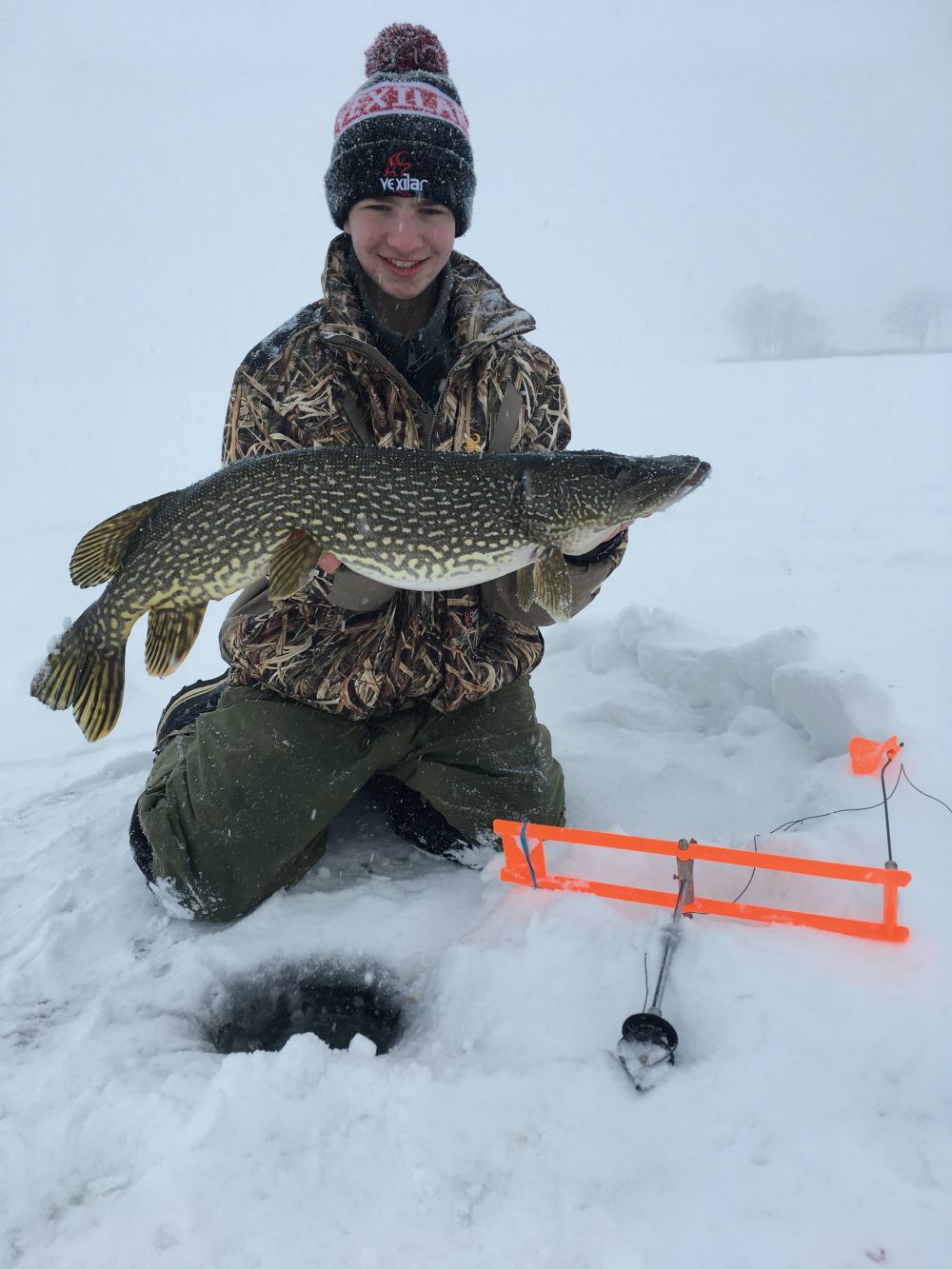 Tip-up with flag while ice fishing for Northern Pike on a lake in